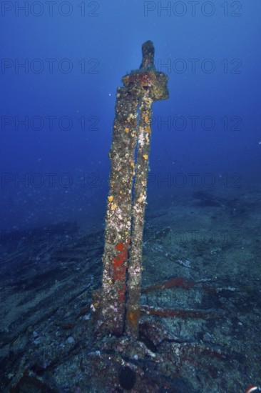 Old rusty part of a shipwreck standing on the seabed, surrounded by blue waters. Dive site wreck Le