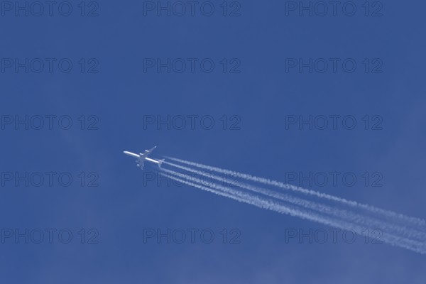 Airbus A340-300 jet aircraft of Lufthansa airlines in flight in a blue sky with vapour trails or
