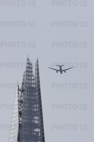 Jet passenger aircraft in flight over The Shard skyscraper building, London, England, United