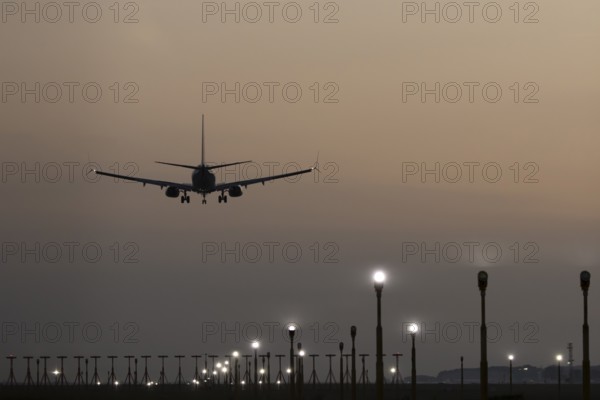 Boeing 737 jet passenger aircraft of Ryanair airlines landing over runway lights at sunset, London