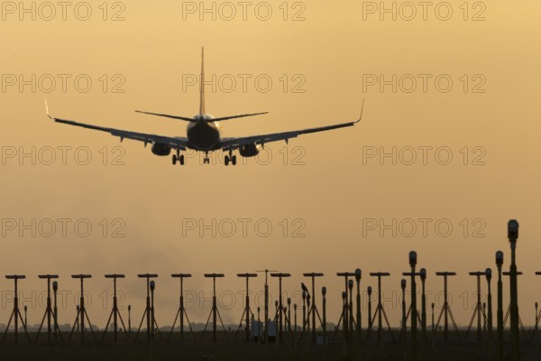 Boeing 737 jet passenger aircraft of Ryanair airlines landing over runway lights at sunset, London