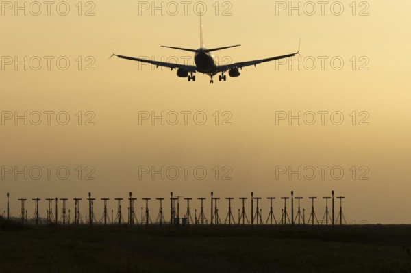 Boeing 737 jet passenger aircraft of Ryanair airlines landing over runway lights at sunset, London