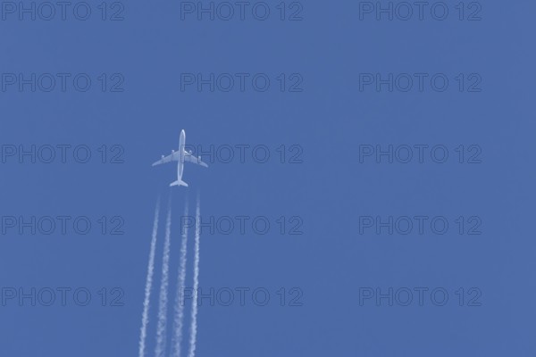 Airbus A340-300 jet aircraft of Lufthansa airlines in flight in a blue sky with vapour trails or