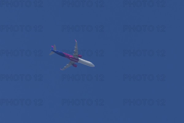 Airbus A321 jet aircraft of Wizz Air airlines in flight in a blue sky, England, United Kingdom