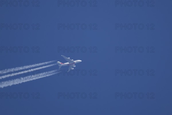 Airbus A380 jet passenger aircraft of Emirates airlines flying with vapour trails or contrails
