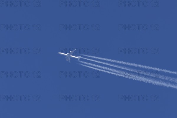Airbus A340-300 jet aircraft of Lufthansa airlines in flight in a blue sky with vapour trails or