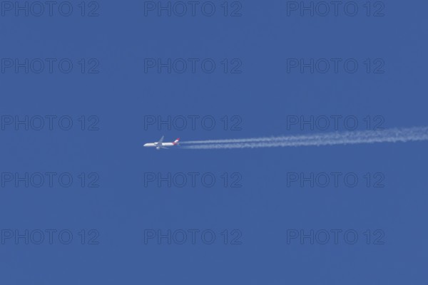 Airbus passenger jet aircraft of Austrian Airlines flying with a vapour trial or contrail behind in