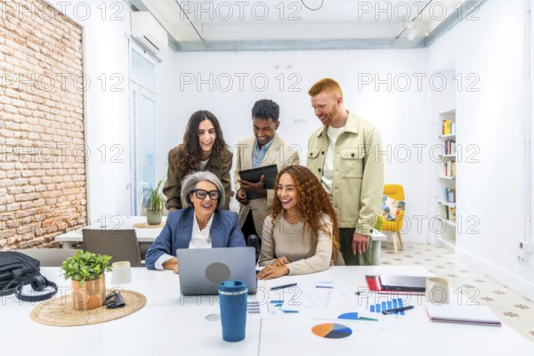 Diverse business team is collaborating and actively discussing financial data shown on a laptop