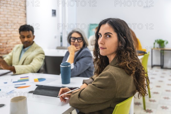 Young businesswoman with curly hair is looking back at the camera while attending a business