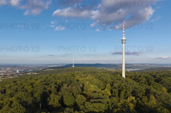 Modern television tower above a green forest and soft clouds in the blue sky, Stuttgart-Degerloch,