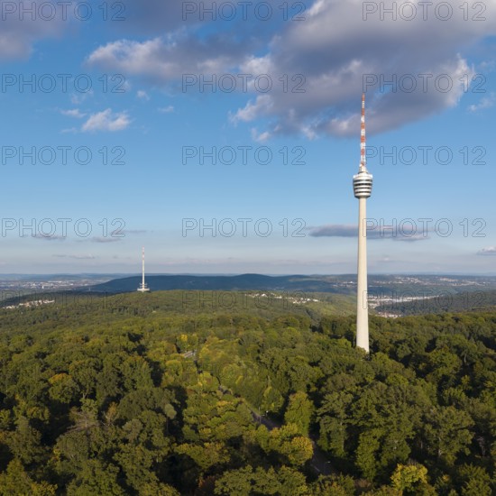 View of the television tower above a green forest under a blue sky with soft clouds,