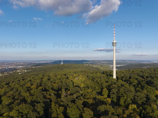The television tower above a wooded area shows a clear sky and scattered clouds,