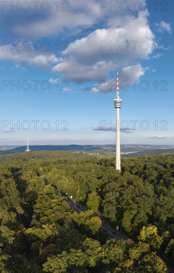 View of the television tower with dense forest and clear sky, soft clouds above,