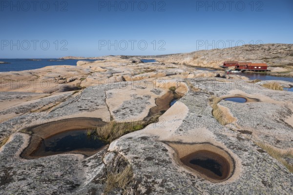 Rocks with rainwater puddles, falun red houses, rocky coast, Bohus granite, Ramsvik, nature reserve