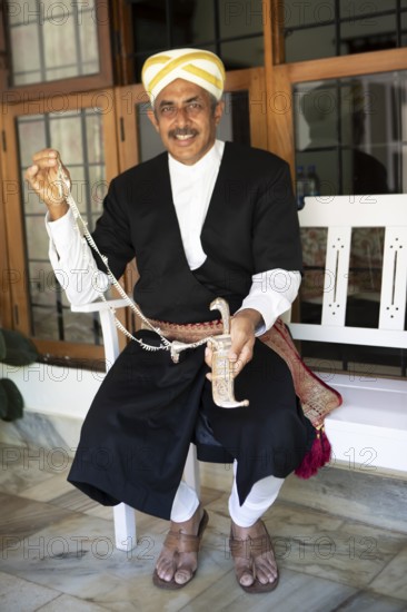 Indian man, 63 years old, from the Kodava clan in traditional dress showing a traditional dagger