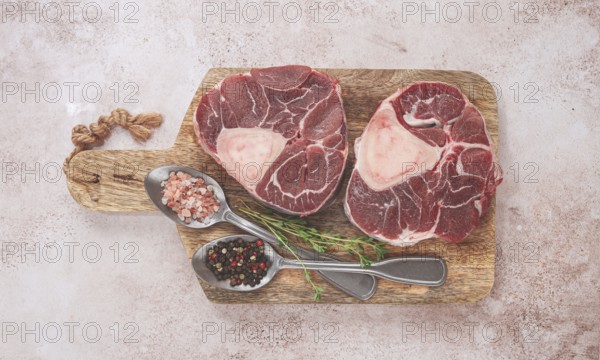 Knuckle on the bone, raw ossobuco meat, on a wooden chopping board, with spices, top view, no