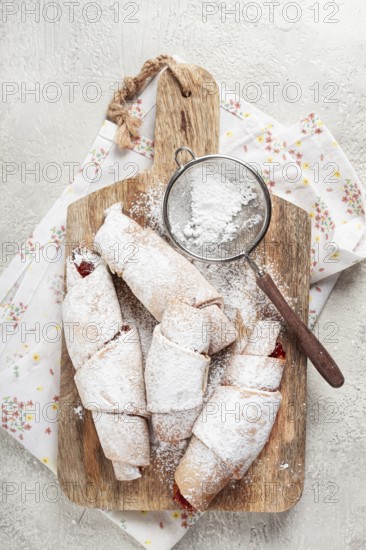 Bagels with filling, sweet pastries, sprinkled with powdered sugar, on a wooden board, dessert,