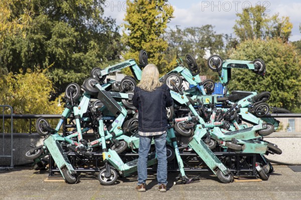 A man looks at an exhibit with stacked e-scooters on the roof terrace of the Haus der Kulturen der