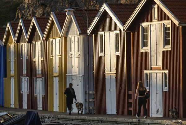 Strollers in front of colourful boathouses in the harbour of Smögen, Smögenbryggan, Västra