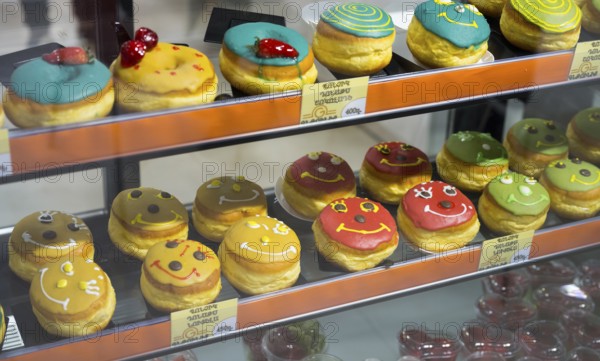 Donuts with colourful glazes and faces in a glass display, Gntunik supermarket, Aragazotn province,