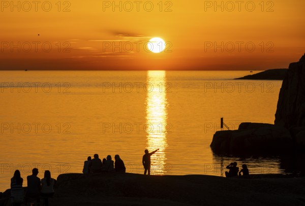 Silhouettes of tourists, sun melting in the sea, sunset, archipelago landscape, Smögen,