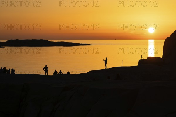 Silhouettes of tourists, sun melting in the sea, sunset, archipelago landscape, Smögen,