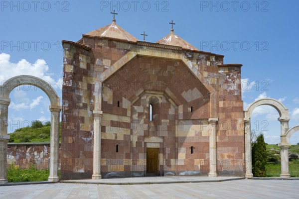 Front view of a stone church with striking arches and three crosses on the roof, Saint Trinity