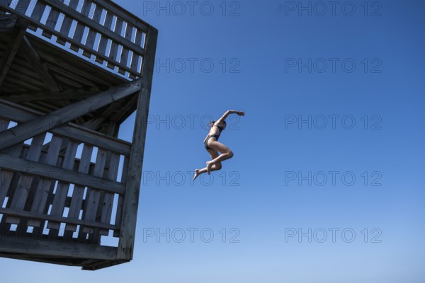Girl jumping from a high wooden diving platform into the sea, lido, Fjällbacka, Bohuslän, West