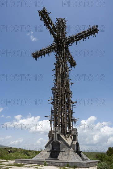 High metal cross with complex structure under a blue sky with clouds, Monument of the Holy Cross,