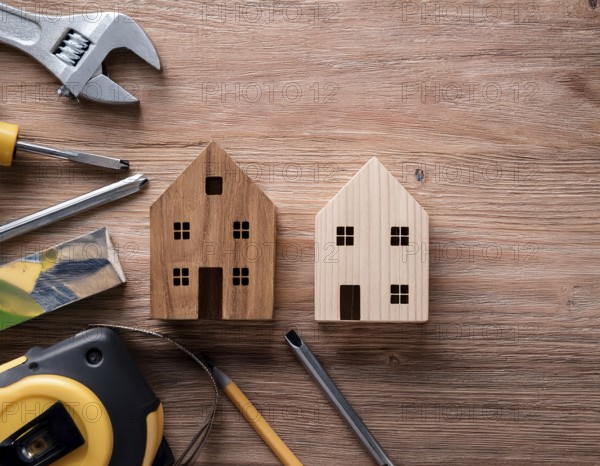 A detailed layout of miniature wooden houses accompanied by various tools on a textured wooden