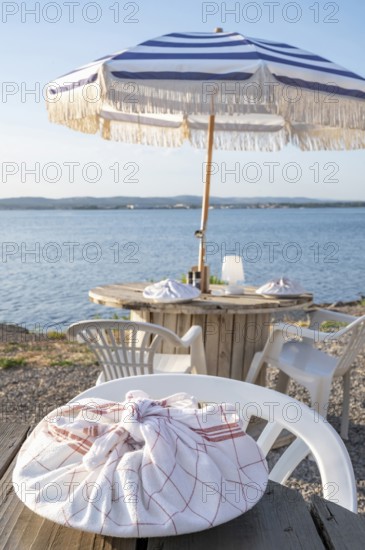 A plate wrapped in a red and white chequered tea towel lies on a rustic wooden table in the