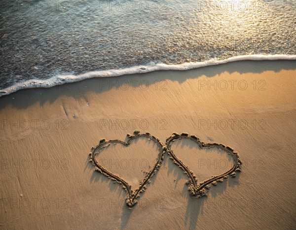 Warm tropical beach with two hearts drawn on the sand, blue waters, and clear skies, invoking