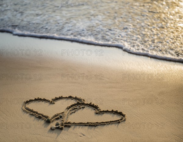 Warm tropical beach with two hearts drawn on the sand, blue waters, and clear skies, invoking