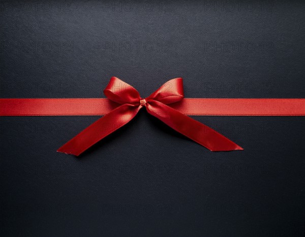 A beautifully wrapped gift box adorned with red satin ribbons forming a bow, contrasting against a