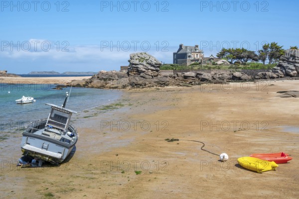 On the harbour beach of Tregastel on the Cote de Granit Rose, small boats lie on the light sand at