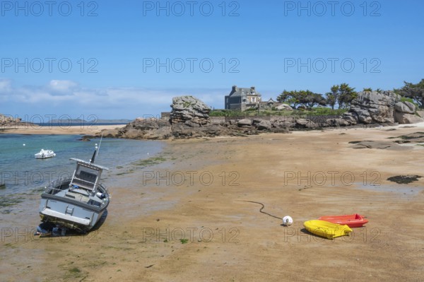 On the harbour beach of Tregastel on the Cote de Granit Rose, small boats lie on the light sand at