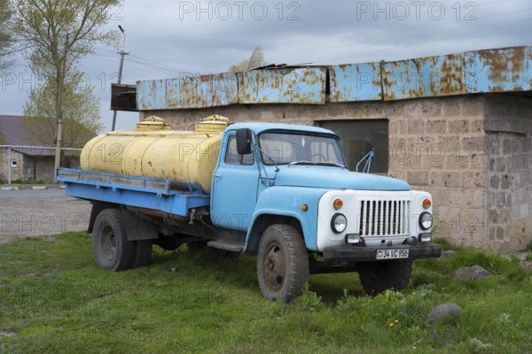 An old blue lorry with yellow tanks stands abandoned in a rural setting, GAZ-53 lorry, tanker,