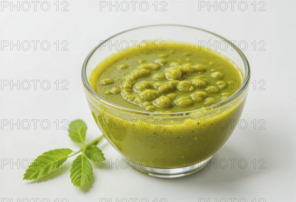 A vibrant image showcasing a bowl of homemade pesto sauce, accompanied by fresh green leaves, set