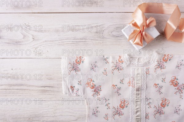 Shirt for newborn toddler and gift box on white wood
