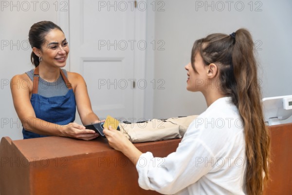Shop assistant smiling and accepting a credit card payment from a customer in a small clothing