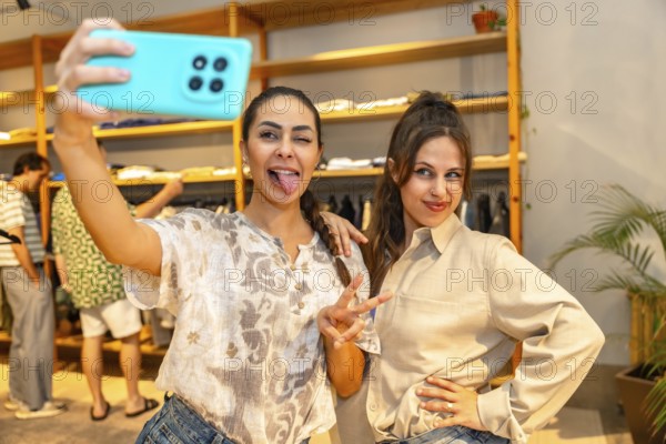 Two friends are having fun taking a selfie with a smartphone, sticking out their tongues, in a