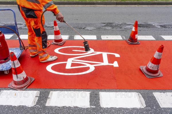 Application of red road surfacing on a cycle lane, inner-city road, so-called cold plastic