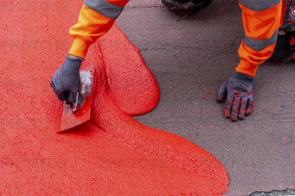 Application of red road surfacing on a cycle lane, inner-city road, so-called cold plastic
