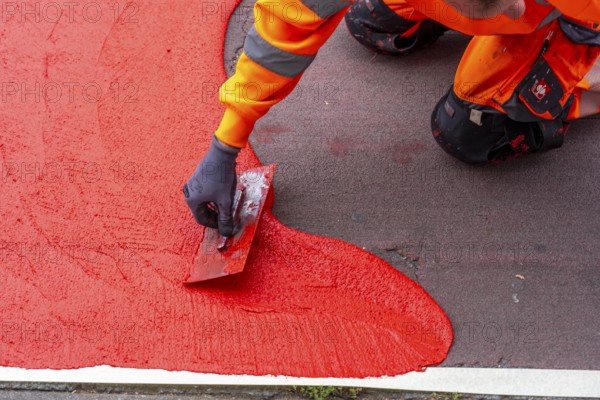 Application of red road surfacing on a cycle lane, inner-city road, so-called cold plastic