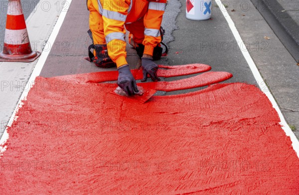 Application of red road surfacing on a cycle lane, inner-city road, so-called cold plastic