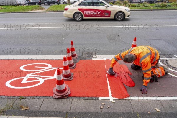 Application of red road surfacing on a cycle lane, inner-city road, so-called cold plastic