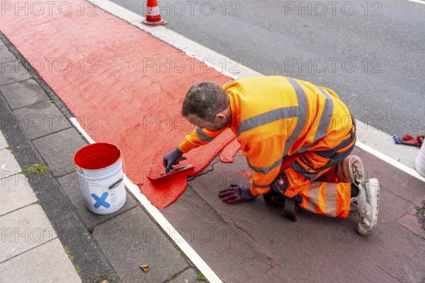 Application of red road surfacing on a cycle lane, inner-city road, so-called cold plastic