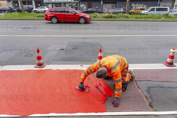 Application of red road surfacing on a cycle lane, inner-city road, so-called cold plastic