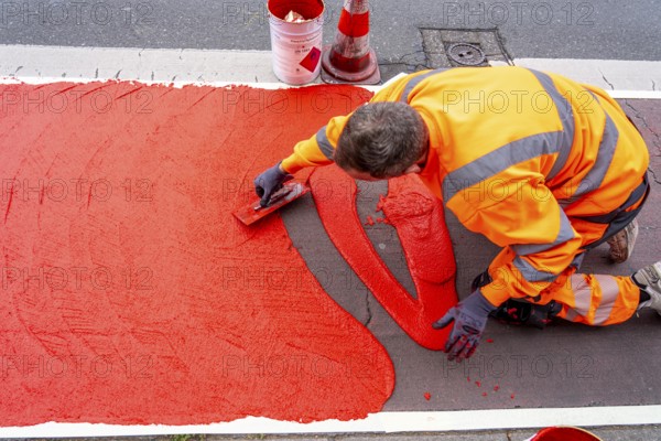 Application of red road surfacing on a cycle lane, inner-city road, so-called cold plastic