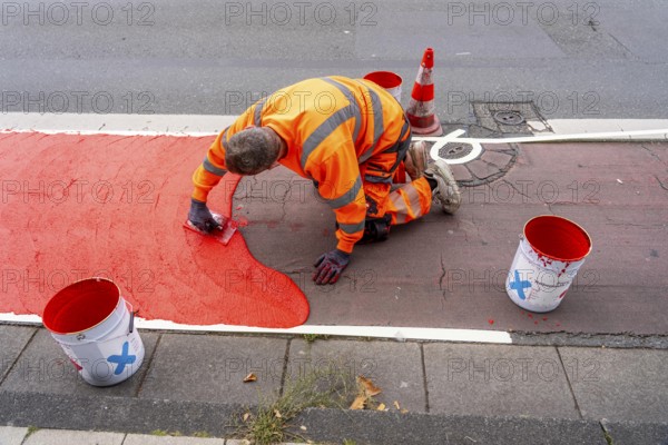 Application of red road surfacing on a cycle lane, inner-city road, so-called cold plastic